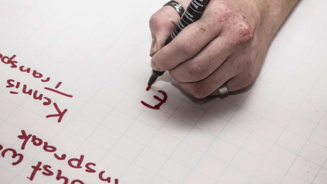 Hand met een rode marker schrijft of een flipover