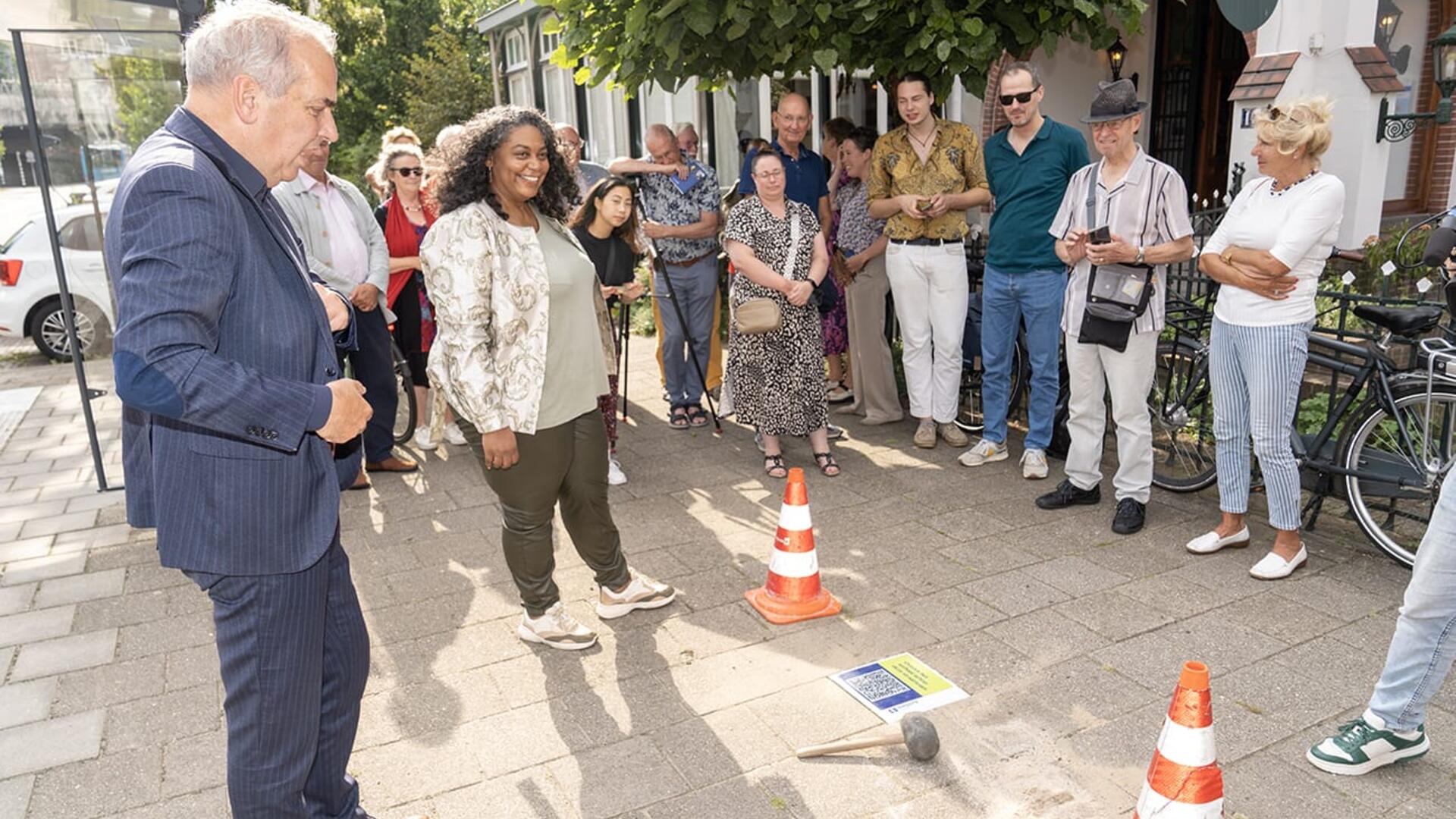 Wethouder Roelofs onthuld de steen, publiek kijkt toe 